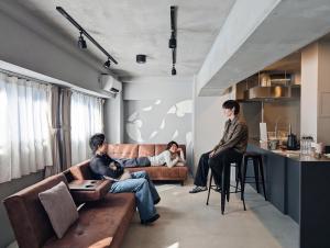 three people sitting on a couch in a living room at ART HOTELS SHIBUYA in Tokyo