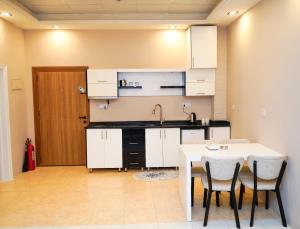 a kitchen with white cabinets and a table and chairs at موتيل رامي سكاي Motel Rami Sky in Erbil +23 photos