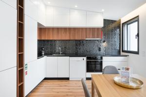 a kitchen with white cabinets and a wooden table at GuestReady – The Mythic Apartments in Porto +140 photos