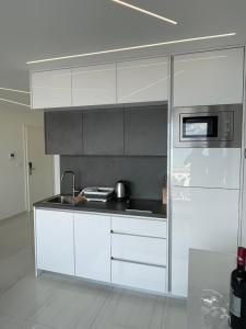 a kitchen with white cabinets and a microwave at Villa San Sebastian-Baška in Baška
