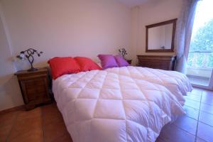 a bedroom with a white bed with red and purple pillows at Casas Rurales el Jardín in Jorquera