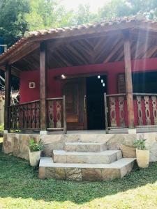 a small house with stairs leading to a door at Chalé da leila in Bocaina de Minas