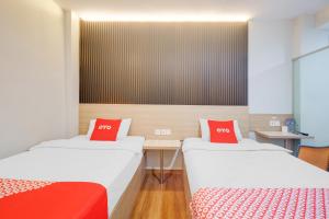 two beds with red pillows in a room at Dancenter Tanjung Duren Near Mall Citraland Formerly Suba Hotel in Jakarta