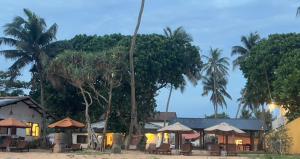 a resort with tables and umbrellas and palm trees at Villa ArthurCC in Hikkaduwa