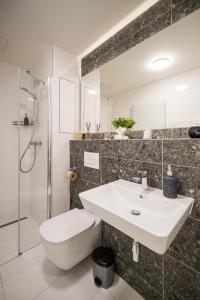 Un baño con lavabo, inodoro y ducha. en Relax Apartments Brno central, en Brno