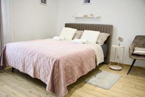 a bedroom with a bed with a pink blanket and a chair at Studio z widokiem na rzekę in Przemyśl