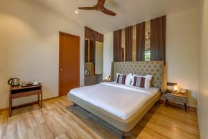 a bedroom with a large white bed and wooden floors at Hillside Harrier Couple's Retreat in Āmbavna