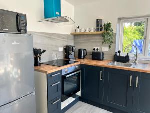 a kitchen with blue cabinets and a stainless steel refrigerator at AeroSuites Luton - SHARED AND PRIVATE Accommodations mins from Luton Airport,FREE selected Breakfast,Adults Only,FREE Parking subject to availability and reservation only, Whats Up number required, Late Self Check In and Out by request only in Luton