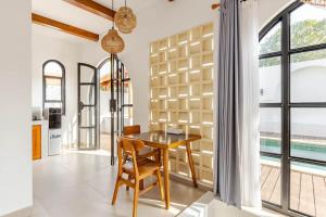 ein Esszimmer mit einem Tisch und einem großen Fenster in der Unterkunft Kanchana Cottages in Uluwatu