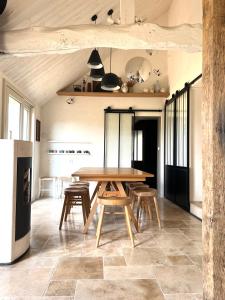 a dining room with a wooden table and chairs at La Maison Vivante, chambres d'hotes au coeur du Perche in Les Étilleux