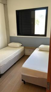 two beds in a room with a window at Pousada Bettys in Ubatuba +16 photos