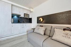 Una sala de estar con un sofá y una cocina. en Le Neptune - Studio face à la plage - Parking, en Fleury