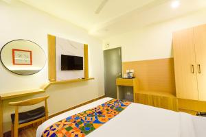 a bedroom with a bed and a mirror and a tv at FabHotel White Ridge-SIa Life Hospital, Kondapur in Kondapur