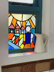 a vase on a shelf with a stained glass window at The Pepper Pot Sleeps 4 Sunlit Garden in Exmouth