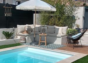 parasol i kanapę przy basenie w obiekcie Jolie villa Lalou Côte d'Azur trois chambres w Fréjus