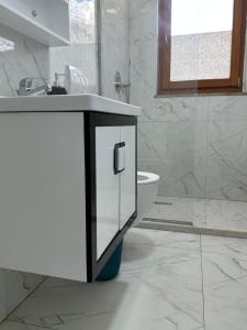 a white bathroom with a sink and a toilet at Petriti theth in Theth +92 photos