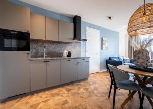 a kitchen with white cabinets and a table and a dining room at Residence Noordstaete - Vakantieappartement Kluut de Luxe in Burgh Haamstede +17 photos