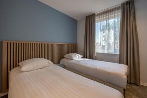 zwei Betten in einem Hotelzimmer mit Fenster in der Unterkunft Residence Noordstaete vakantieappartement Lepelaar in Burgh Haamstede