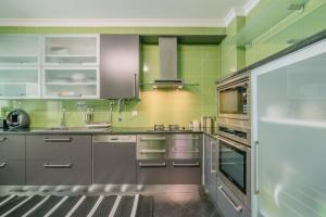 eine Küche mit Küchengeräten aus Edelstahl und grünen Wänden in der Unterkunft Casa da Rita in Olhão