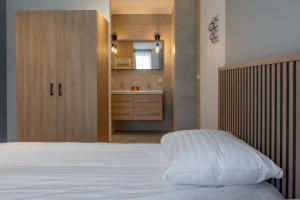 ein Schlafzimmer mit einem weißen Bett und ein Badezimmer in der Unterkunft Residence Noordstaete - Vakantieappartement Lepelaar de Luxe in Burgh Haamstede
