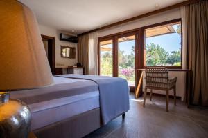 a bedroom with a bed and a chair and a window at XUMA Bungalows in Bodrum City