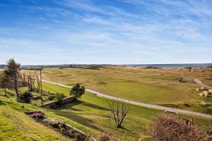 a view of a field of grass with the ocean in the background at Penthouse Golf View Apartments in Lossiemouth