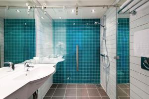 a bathroom with two sinks and a shower with blue tiles at Scandic Narvik in Narvik