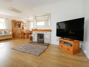 a living room with a fireplace and a flat screen tv at Swn Y Wylan in Abersoch