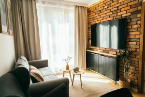 a living room with a couch and a television on a brick wall at Apartament Ulubiony Mariental Residence in Szklarska Poręba