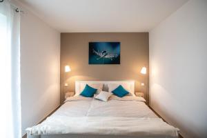 a bedroom with a white bed with blue pillows at Claudia's Seeherz in Wasserburg am Bodensee