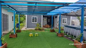 un patio con una cubierta azul y algunas mesas y sillas en Laman Abah Staycation, en Jenjarum