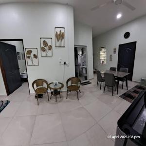 una sala de estar con una mesa y sillas en Laman Abah Staycation, en Jenjarum
