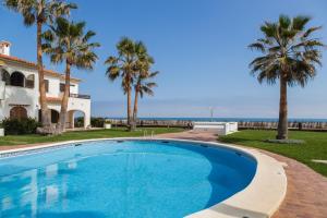 una piscina davanti a una casa con palme di Nueva Playa a Denia