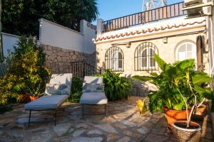 a patio with two chairs and plants in front of a building at Suite 5 in Cala del Moral