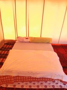 Posto letto in tenda con piumone bianco. di Camp Les Bedouins iriki a Bou Guir