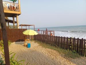 a yellow umbrella on the beach next to a fence at Adinam's Beach Retreat in Nyanyanu