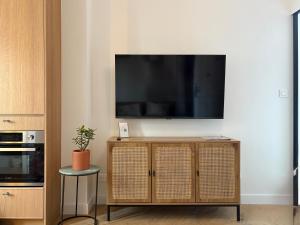 ein Wohnzimmer mit einem Fernseher an der Wand in der Unterkunft Home Chic Home - Le Cocon de Paris La Défense in La Garenne-Colombes