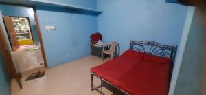 a small room with a red bed in a blue room at Sharvati Backwater Homestay in Haldipur