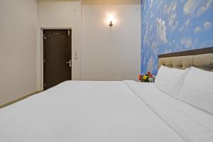 a large white bed in a room with a door at Capital O Maharana Palace in Udaipur