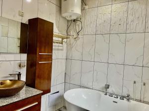 a bathroom with a white tub and a sink at Maison Chic et confortable à la poste centrale in Yaoundé +30 photos