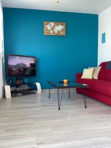 a living room with a red couch and a blue wall at Le grand large - Draps et ménage inclus in Le Barcarès
