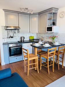 a kitchen with white cabinets and a table and chairs at Georgina Portview- Pet Free-Allergy Friendly in Porthmadog +8 photos