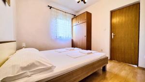 a bedroom with a bed with white sheets and a wooden door at Balcon del Mar in Dramalj