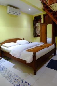 a bedroom with a large bed with white sheets at Villa Alicia - Pavillion Lily in Yogyakarta