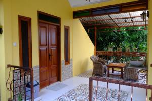 a porch with a wooden door and a table and chairs at Villa Alicia - Pavillion Lily in Yogyakarta