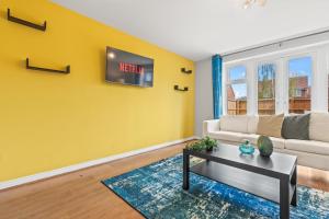 a living room with a couch and a tv on a wall at Stylish 4 Bedroom House in St Neots w Free Parking in Saint Neots