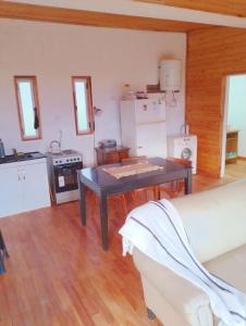 ein Wohnzimmer mit einem Tisch und einer Küche in der Unterkunft Družina Embalse Calamuchita in Embalse