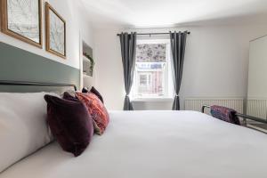 a bedroom with a white bed with pillows and a window at Ness Heights, Spacious City Centre Townhouse in Inverness +65 photos