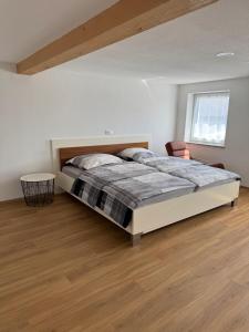 a bedroom with a bed and a wooden floor at Ferienwohnung Altheim in Thalheim
