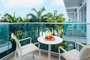 a balcony with a table and chairs and palm trees at Sonesta Maho Beach All Inclusive Resort Casino & Spa in Maho Reef